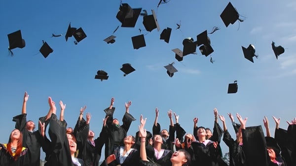 Los graduados de la Sardis Secondary School lanzan sus sombreros al cielo azul durante la ceremonia de graduación.
