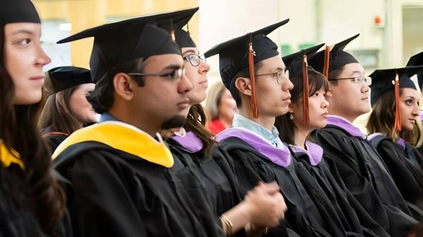 Un grupo de graduados de la Saunders Secondary School está de pie en ropa académica durante la ceremonia de graduación.