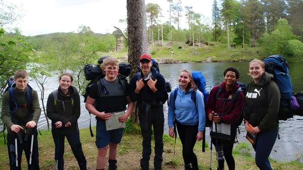 Estudiantes de Scarborough College están juntos en un área boscosa cerca de un cuerpo de agua.