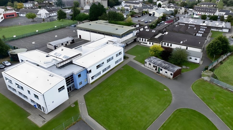 El amplio campus de Scoil Dara con arquitectura moderna y tradicional en medio de prados verdes y árboles en una pintoresca ciudad.