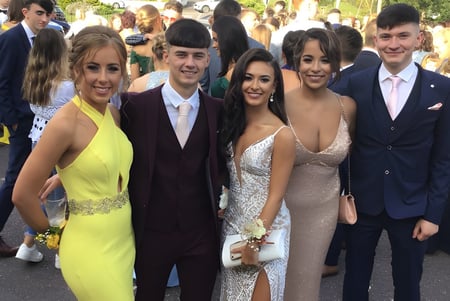 Un grupo de estudiantes de la Scoil Mhuire gan Smál posan juntos afuera frente a edificios y árboles.