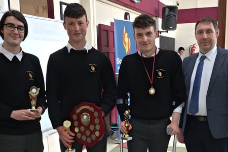 Cuatro estudiantes de la Scoil Mhuire Kanturk sostienen juntos premios y trofeos.