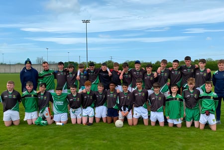 Estudiantes de la Scoil Ruáin posan juntos como equipo de fútbol en un campo.