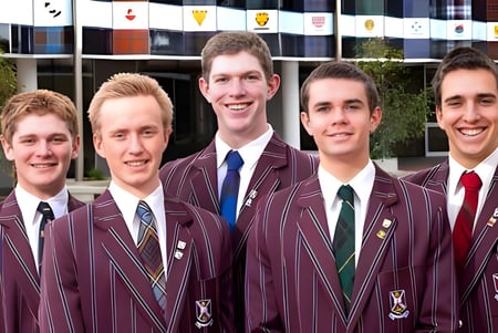 Un grupo de estudiantes en uniformes escolares color burdeos está frente a un edificio con banderas en el terreno del Scotch College.