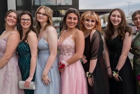 Un grupo de jóvenes mujeres vestidas de fiesta posan juntas frente a un edificio en el terreno del Scots PGC College.