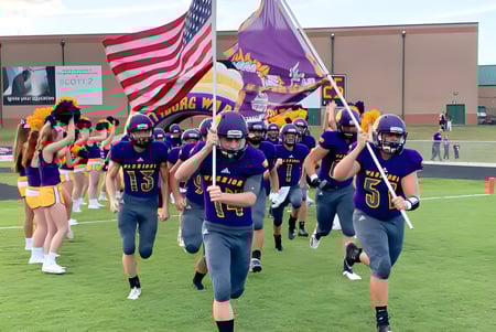 Un grupo de jugadores de fútbol americano en uniformes morados lleva banderas y entra al campo en el campus de la Scottsburg High School.