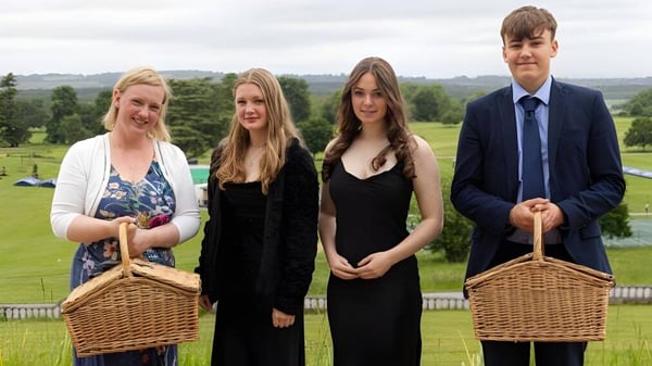 Cuatro estudiantes del Seaford College están juntos en una pradera con colinas y árboles de fondo.