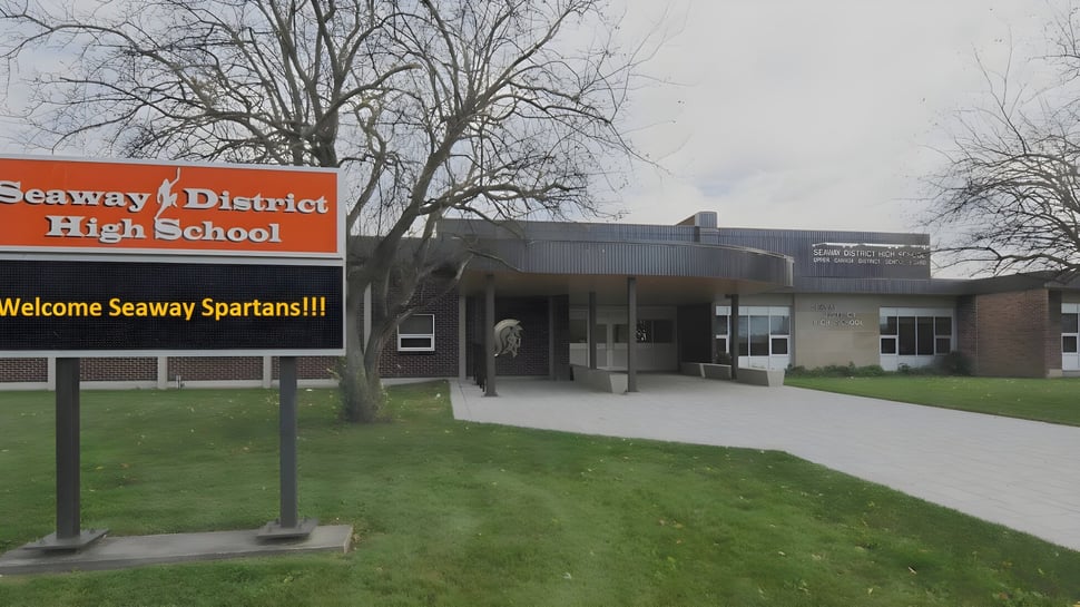 La vista exterior de Seaway District High School con un gran cartel de bienvenida para los Seaway Spartans en primer plano.