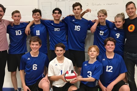 Un grupo de estudiantes de la Selkirk Secondary School posan como equipo de voleibol en el gimnasio.