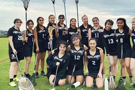 Un grupo de alumnas en uniformes escolares negros posan en un campo en el campus del Selwyn College.