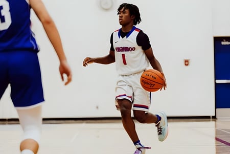 Un jugador de baloncesto con camiseta blanca dribla el balón en la cancha de la Semiahmoo Secondary School.