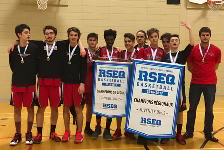 Estudiantes del Séminaire de Chicoutimi sostienen juntos un banner de campeonato en el gimnasio después de un torneo de baloncesto.