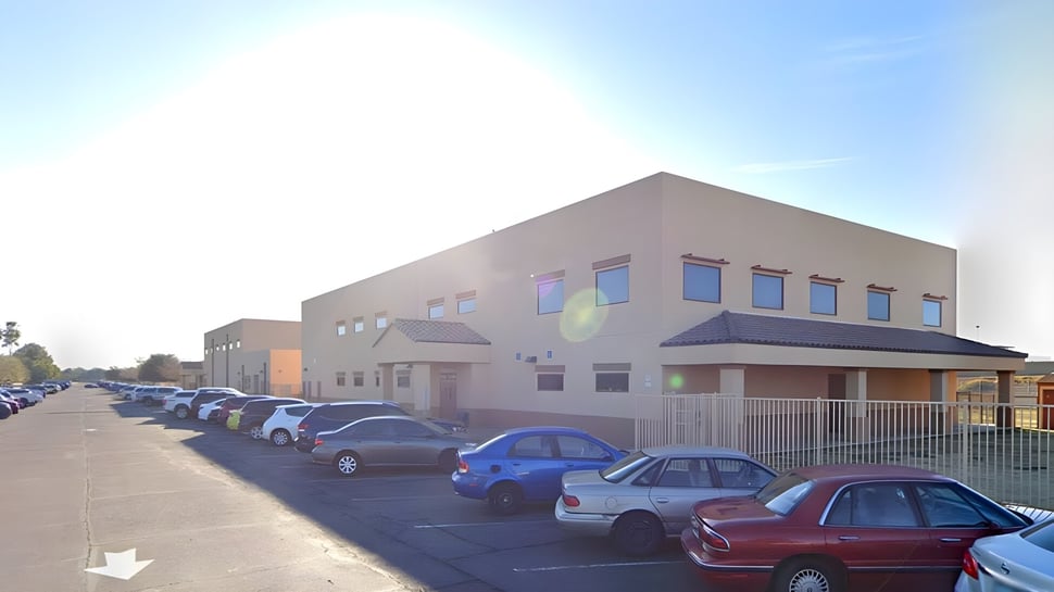 El edificio escolar de varios pisos de la Sequoia Charter High School con el estacionamiento y coches aparcados en primer plano.