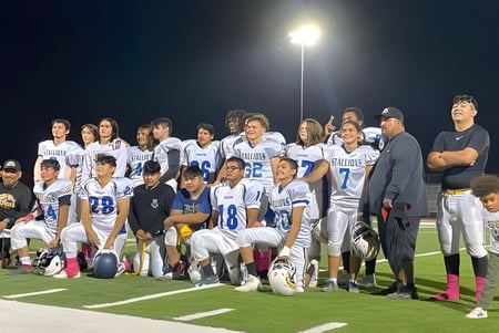 Un grupo de jóvenes futbolistas posando de noche en el campo de fútbol iluminado de la Sequoia Charter High School.