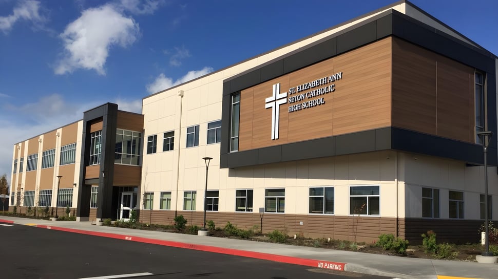 El moderno edificio de varios pisos de la Seton Catholic High School con una gran cruz en la fachada bajo un cielo azul.