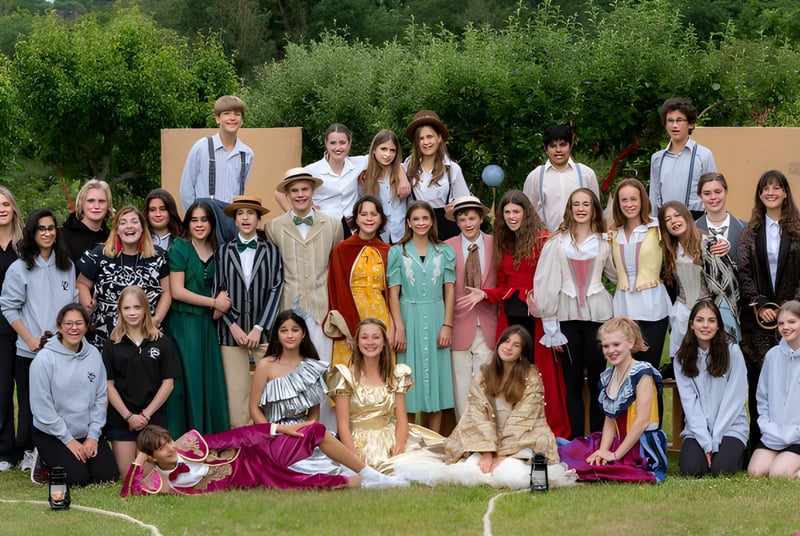 Un grupo de estudiantes de la Sevenoaks School está afuera frente a un paisaje verde.