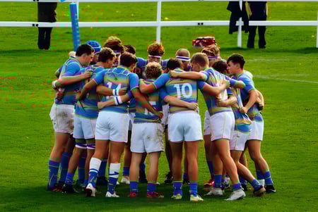 Un grupo de jóvenes atletas en uniformes azules y blancos en un campo deportivo de la Sherborne School.