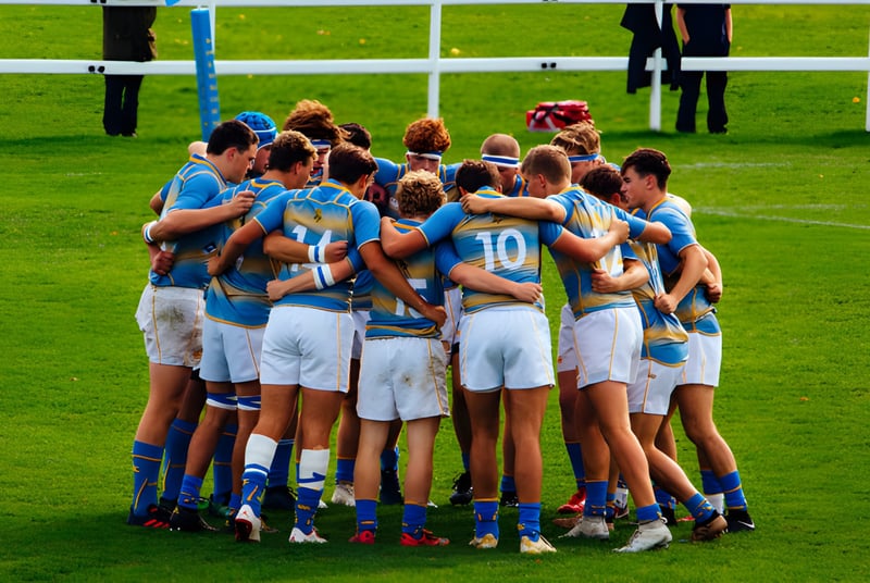Un grupo de jóvenes atletas en uniformes azules y blancos en un campo deportivo de la Sherborne School.