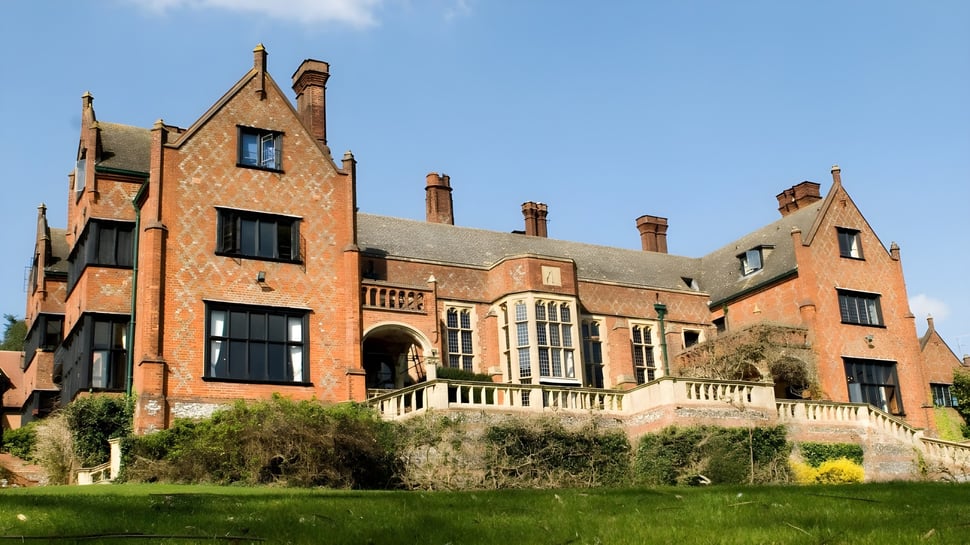 La impresionante mansión en el campus del Shiplake College se encuentra en una colina cubierta de hierba y está rodeada de vegetación verde.