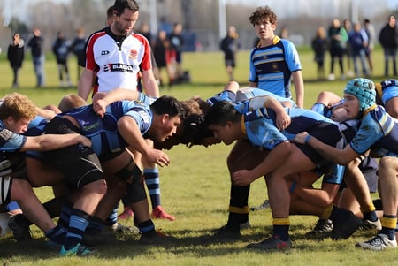Los jugadores de rugby de Shirley Boys' High School forman un agrupamiento en el campo frente a los espectadores.