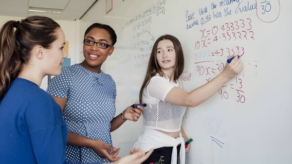 Tres estudiantes trabajan juntos en una pizarra durante una actividad de aprendizaje en el campus de la Shrewsbury School.