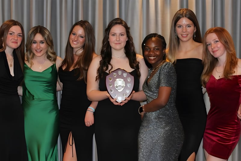 Un grupo de mujeres con ropa formal posan frente a una cortina gris en el campus de la Sibford School.