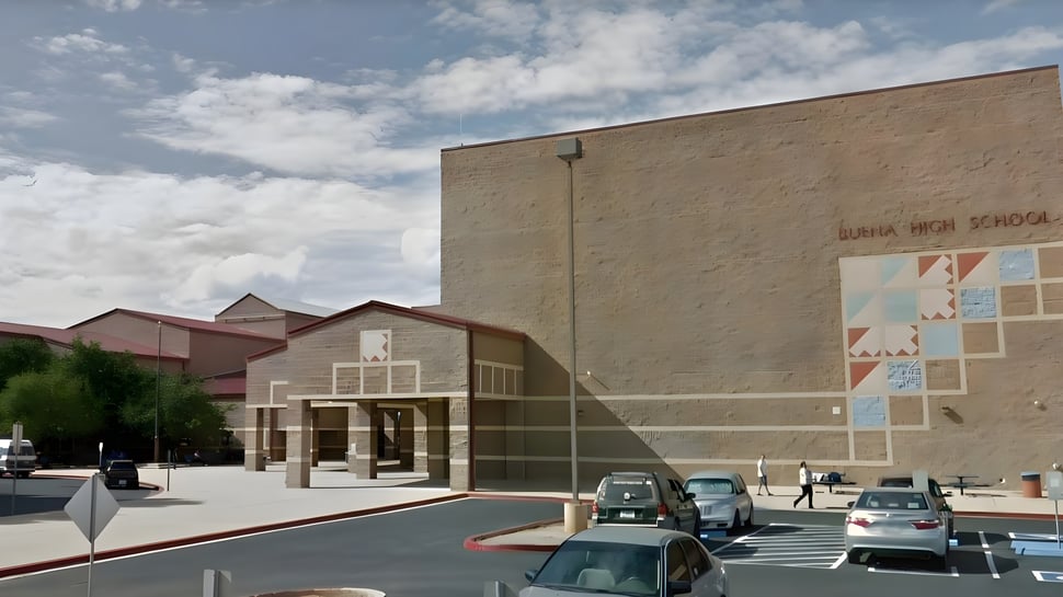 El edificio de ladrillo de varios pisos del Sierra Vista Unified School District con entrada cubierta y estacionamiento delante.