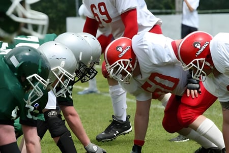 Estudiantes del Silverthorn Collegiate Institute están en camisetas rojas y blancas en el campo de fútbol frente a sus oponentes en camisetas verdes y blancas.