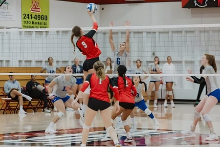 Jugadoras de voleibol de la Simpson University juegan un partido frente a espectadores.