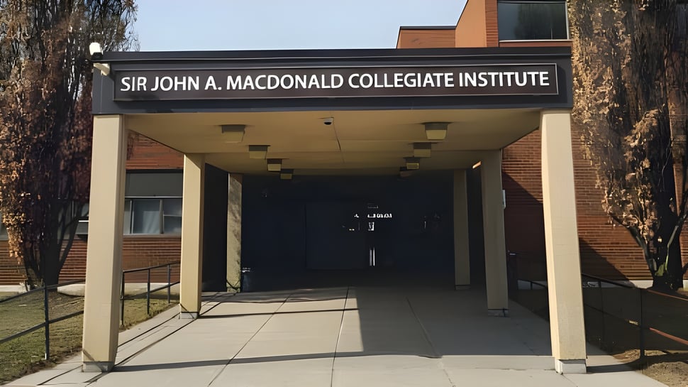 Se ve el área de entrada del Sir John A. Macdonald Collegiate Institute con un camino cubierto y un edificio de ladrillos.