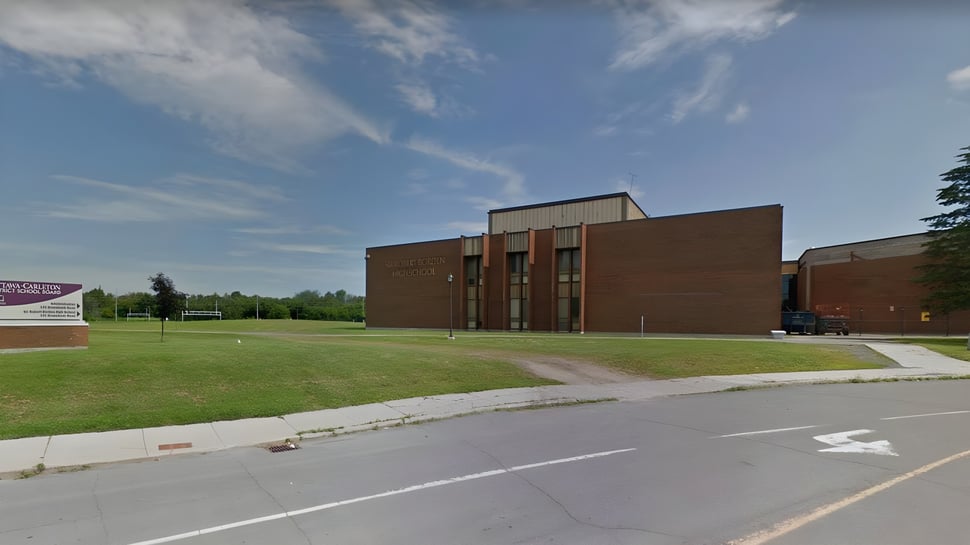 El edificio de ladrillo de la Sir Robert Borden High School se encuentra en un área cubierta de hierba bajo un cielo azul con nubes.