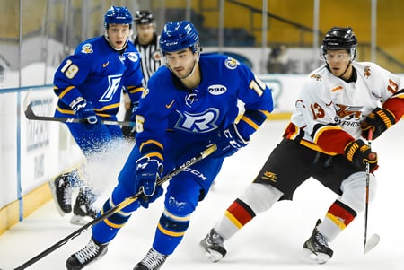 Estudiantes de la Sir Wilfrid Laurier Secondary School juegan un partido de hockey en la pista de hielo con espectadores al fondo.