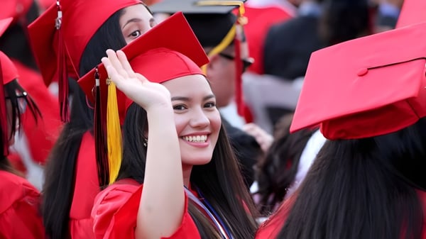 Un grupo de graduadas y graduados de la Sisler High School en togas y birretes rojos está juntos.