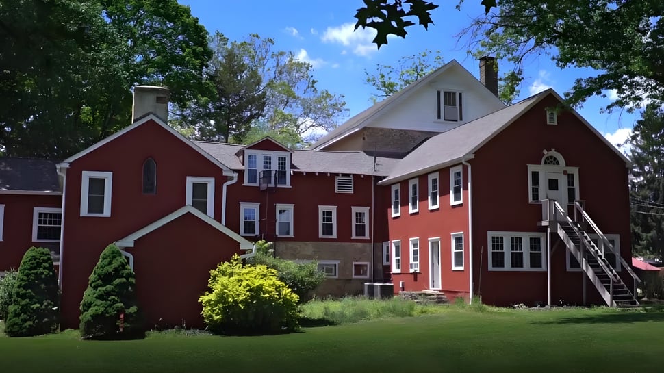El edificio de ladrillo rojo de la Solebury School está rodeado de exuberante vegetación y se encuentra frente a un paisaje pintoresco.
