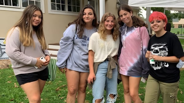 Un grupo de cinco estudiantes se encuentra junto a un edificio en el campus de la Solebury School.