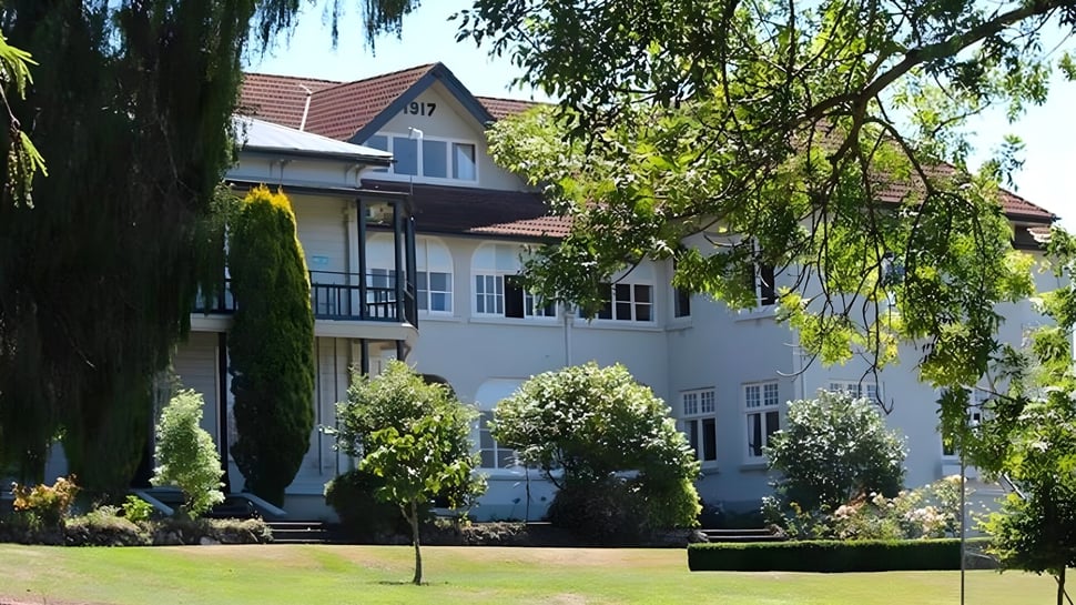 El edificio de varios pisos del Solway College está rodeado de un jardín bien cuidado con abundante vegetación.