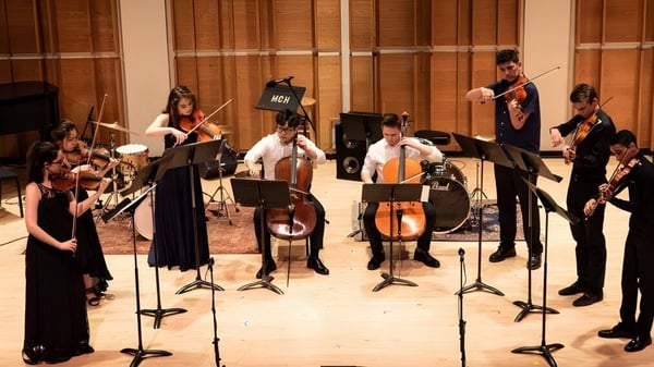 Estudiantes de la Somervale School tocan diferentes instrumentos durante un concierto en una sala de conciertos de madera.