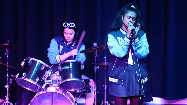 Dos alumnas y alumnos del Southern River College actúan juntos en el escenario con batería y canto.