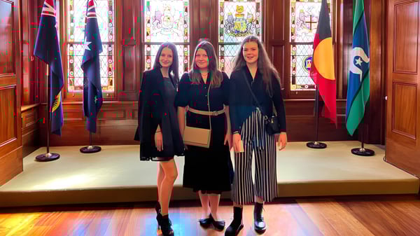 Tres estudiantes en ropa formal negra están en el magnífico salón del Springbank Secondary College.