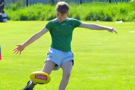 Un estudiante de St Ailbe's School corre por un campo de hierba y juega con un balón de fútbol.