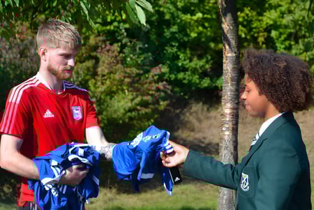 Dos estudiantes de St. Alban's Catholic High School conversan al aire libre frente a una vegetación verde.