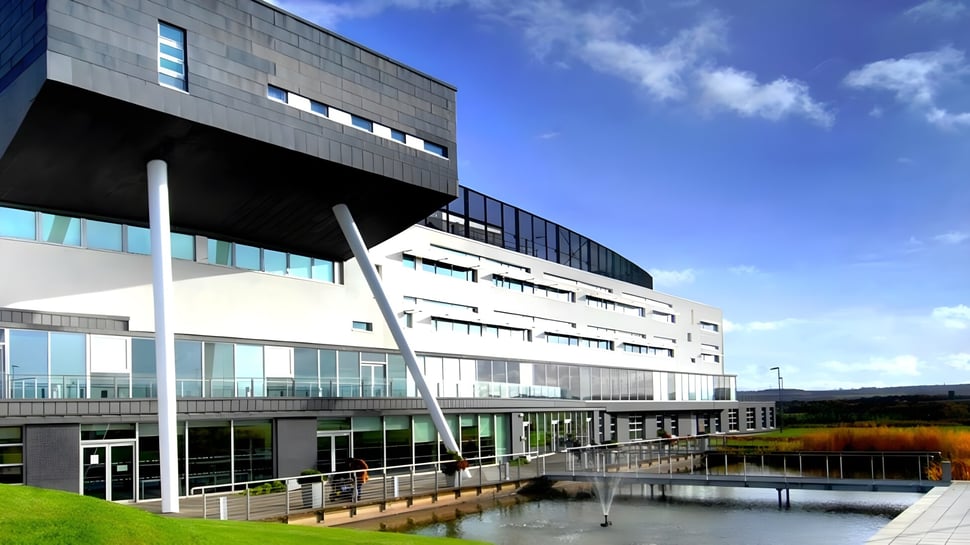 El moderno edificio del St. Andrew's College se encuentra frente a un estanque y está rodeado de vegetación verde.