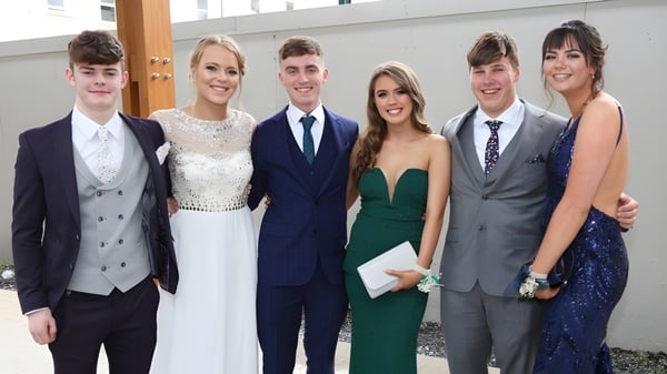 Un grupo de personas está frente al moderno edificio del St. Andrew's College en un evento formal.