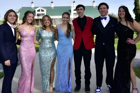 Un grupo de personas elegantemente vestidas está frente al edificio histórico en el campus del St. Andrew's College.