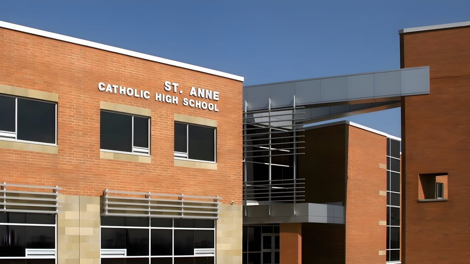 El moderno edificio de ladrillo de la St. Anne Catholic High School se ve ante un cielo azul claro.