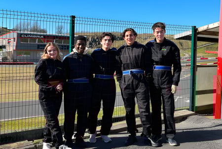 Un grupo de estudiantes en uniformes negros está frente a un área exterior cercada en el campus de la St. Bees School.
