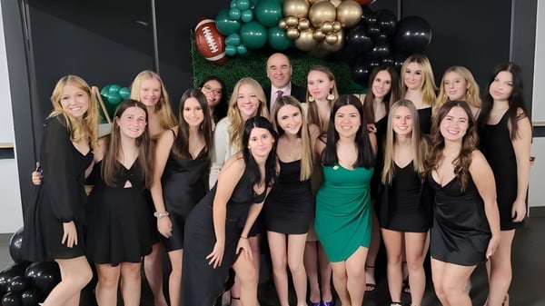 Un grupo de jóvenes mujeres en ropa formal posan frente a globos de colores en el terreno de la St. Benedict Catholic Secondary School.