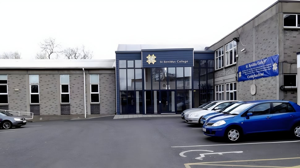 El moderno edificio de varios pisos con entrada y coches aparcados en el terreno del St. Benildus College.