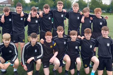 Un grupo de jóvenes futbolistas en camisetas negras en el campo deportivo del St. Benildus College.