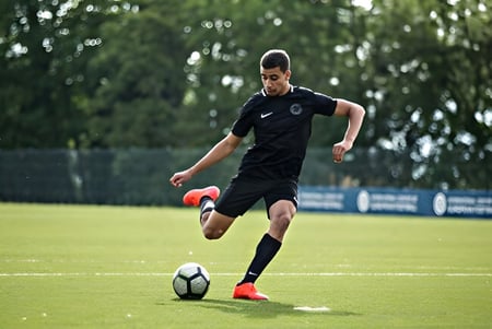 Un jugador de fútbol con una camiseta negra corre con el balón en el campo del St. Bricin’s College.